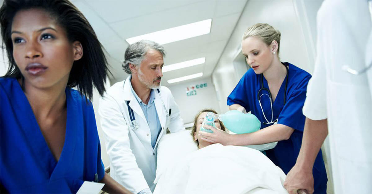 Hospital emergency department with staff at a computer and an empty gurney